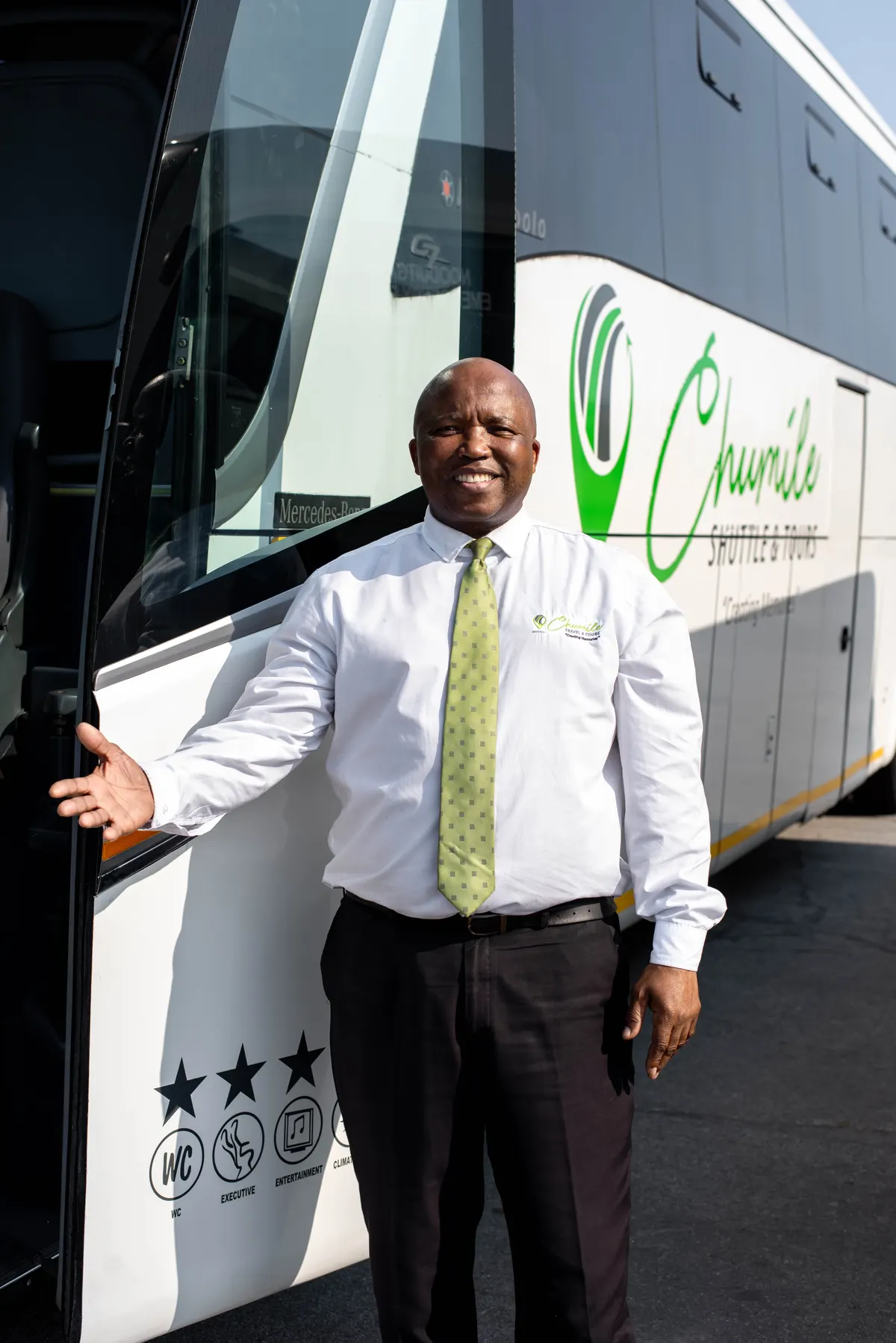 A Chumile driver welcoming passengers at the door of a coach